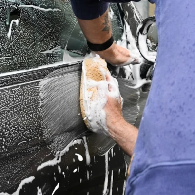 A man washing the side of a car with a sponge